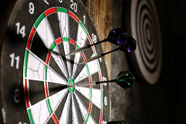 Nahaufnahme von Dartscheibe mit Pfeilen darin.