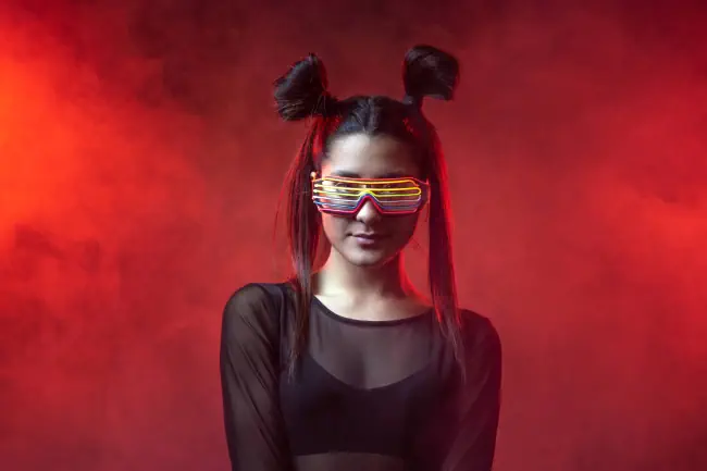 Porträt einer wunderschönen Cybermodellfrau, die in einem virtuellen Technologieumfeld mit Brille und Neonlicht im Hintergrund.