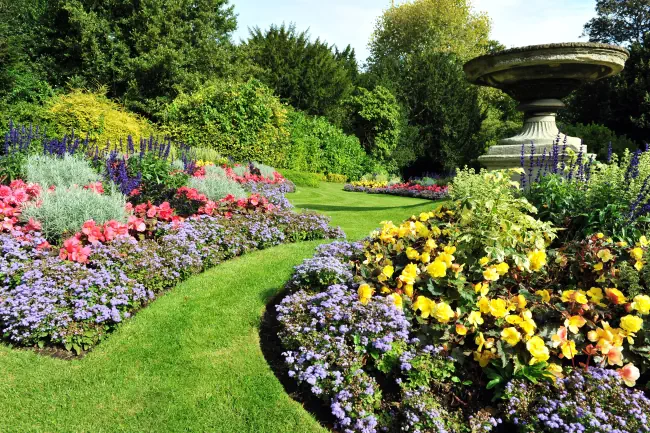 Blumenbeete, Grasweg und Ziervase im Garten