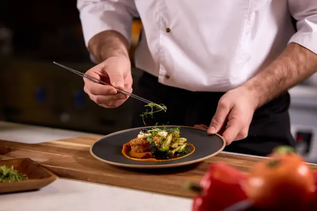 Kulinarik-Bild - Koch-Salat mit frischen Grün, der den Restaurantgästen vor der Zubereitung eine raffinierte Note verleiht