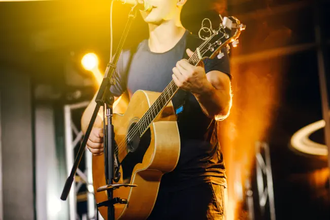 Der Sänger spielt eine akustische Gitarre und singt auf einem Konzert