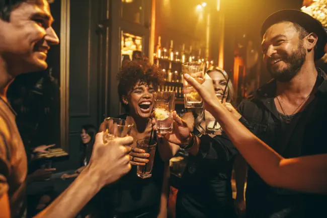 Vier Personen lachen und feiern etwas.