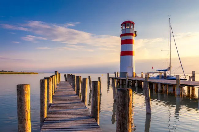 Leuchtturm am Neusiedler See, Podersdorf am See, Burgenland, Österreich. Leuchtturm bei Sonnenuntergang in Österreich. Holzsteg mit Leuchtturm in Podersdorf am Neusiedler See in Österreich.