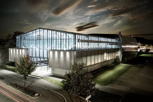 Die Helmut List Halle bei Nacht, eindrucksvoll beleuchtet mit warmem Licht, das die moderne Architektur und die Glasfassade betont