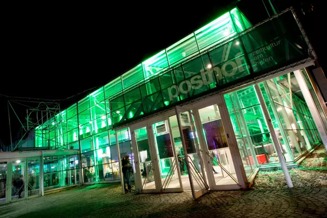 Grün beleuchteter Eingang des Posthof Linz bei Nacht